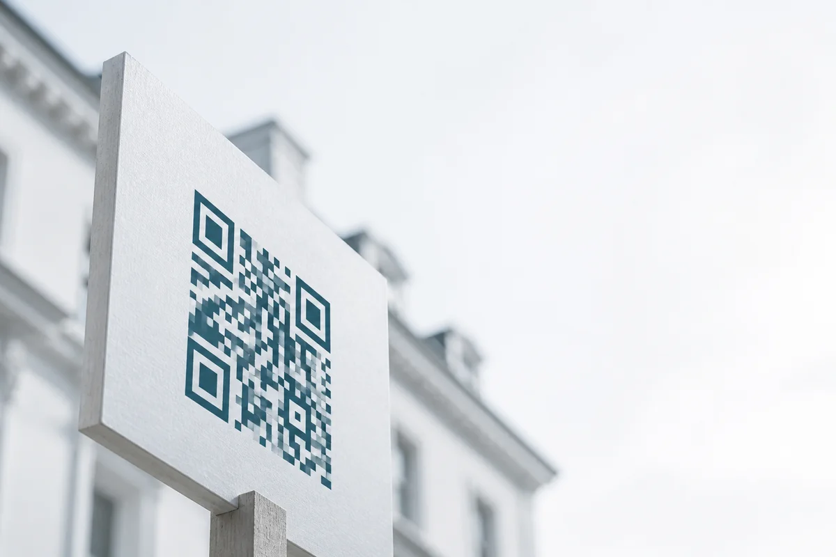A blank estate agent board on a wooden post outside a Victorian terraced house.